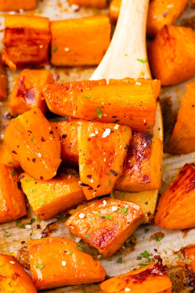 Perfectly roasted sweet potatoes on a serving spatula on a baking sheet.