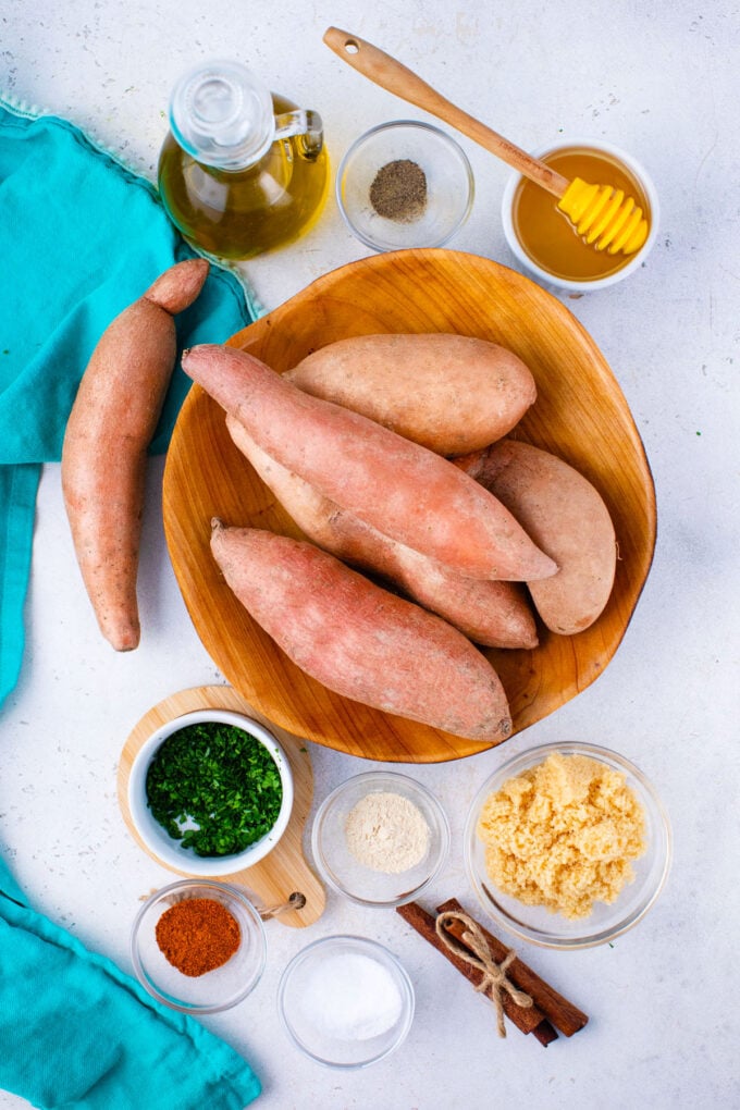 Overhead shot of roasted sweet potatoes ingredients in bowls on a white surface.