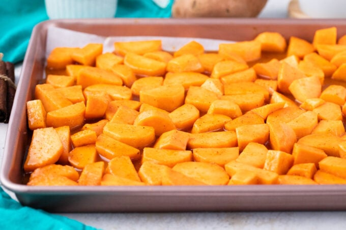 Sweet potato chunks in a brown sugar glaze on a baking sheet.