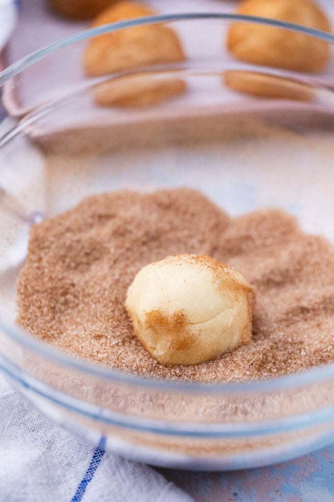 Rolling cream cheese cookie balls in cinnamon sugar mixture.