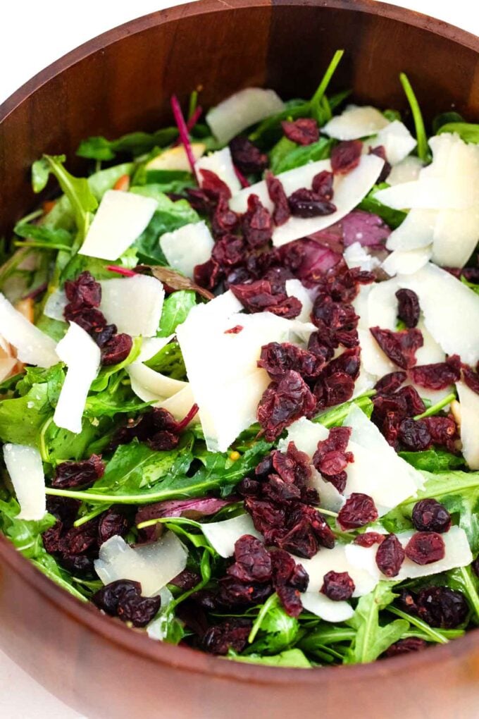 greens, parmesan, and cranberries in a salad bowl