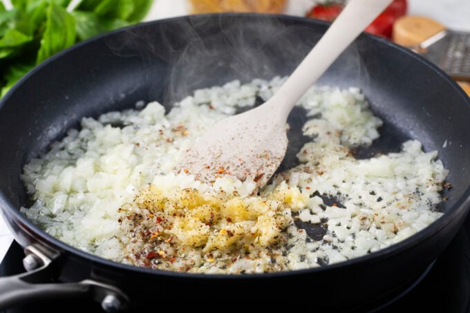 Sautéing onion, garlic, and seasonings in a skillet.