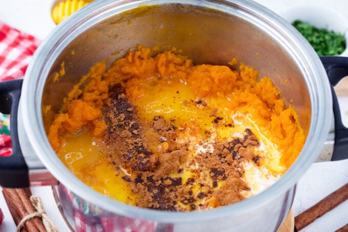 Seasoning mashed sweet potatoes with cinnamon, nutmeg, and maple syrup.