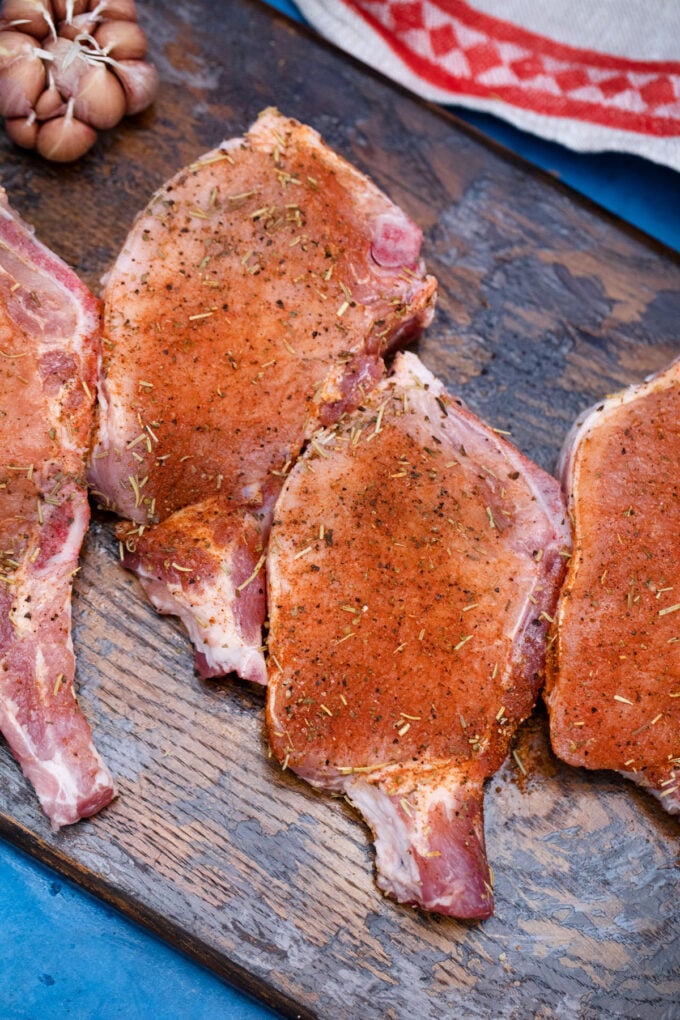 Rubbing spice mixture onto pork chops.