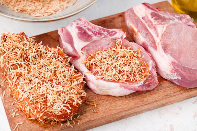 Coating pork chops in parmesan seasoning mix.