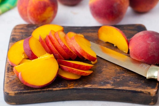 Slicing peaches on a wooden cutting board.
