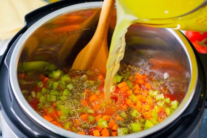 Adding ingredients for homemade Instant Pot lasagna soup to the pot.