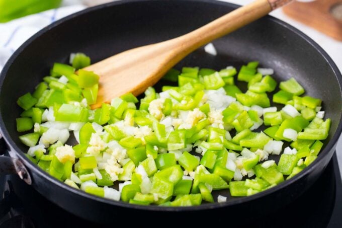 Cooking onion and bell pepper in a skillet.