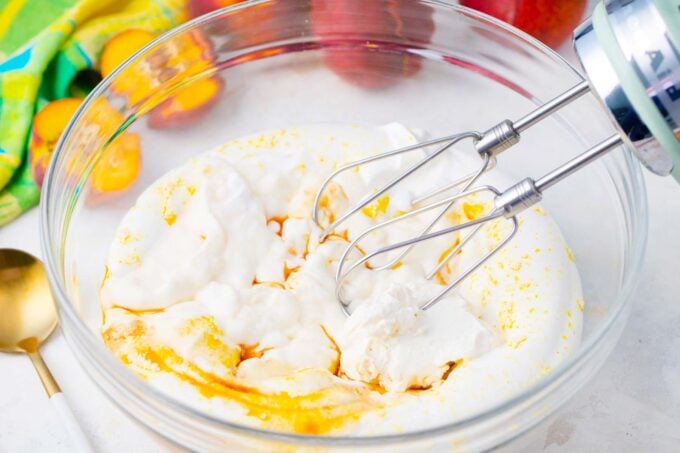 Whipping cream cheese, cheesecake pudding mox and vanilla in a bowl.