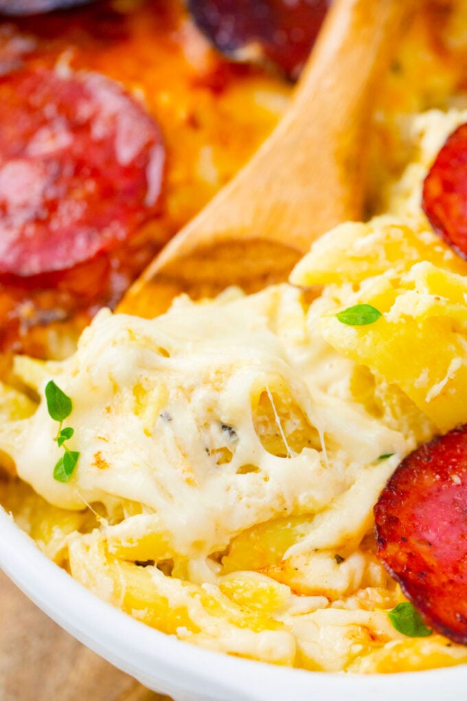A serving spoon of cheesy white pizza casserole.