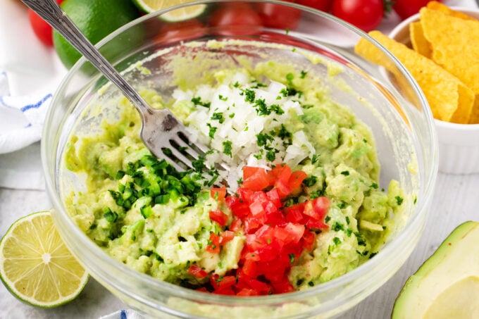 Mixing parsley, onion, tomatoes, and jalapenos in guacamole.