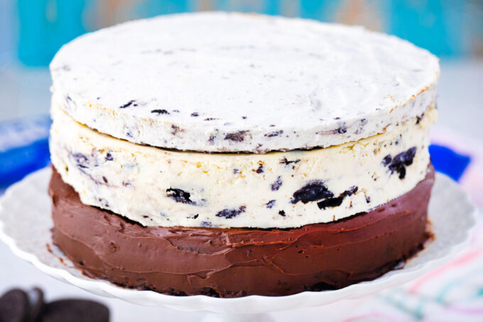 Assembling dream extreme Oreo cake with chocolate cake layer, Oreo cheesecake layer, and Oreo mousse layer.