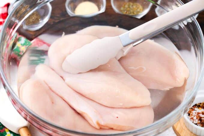 Brining chicken breasts in a bowl.