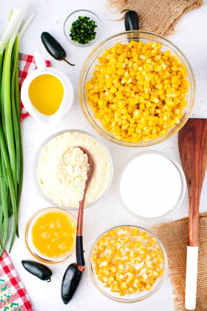 Overhead shot of corn casserole ingredients in bowls on a white surface.