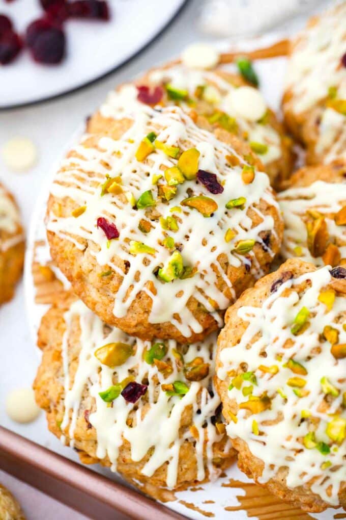 a pile of cranberry oatmeal cookies topped with white chocolate and pistachios