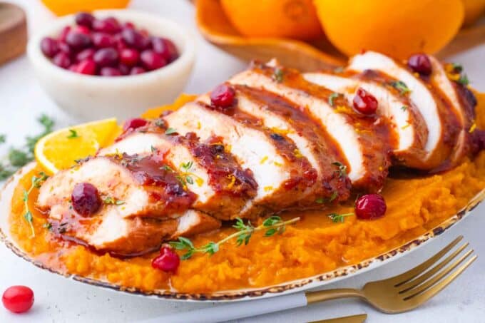 sliced cranberry orange turkey breast on top of mashed sweet potatoes