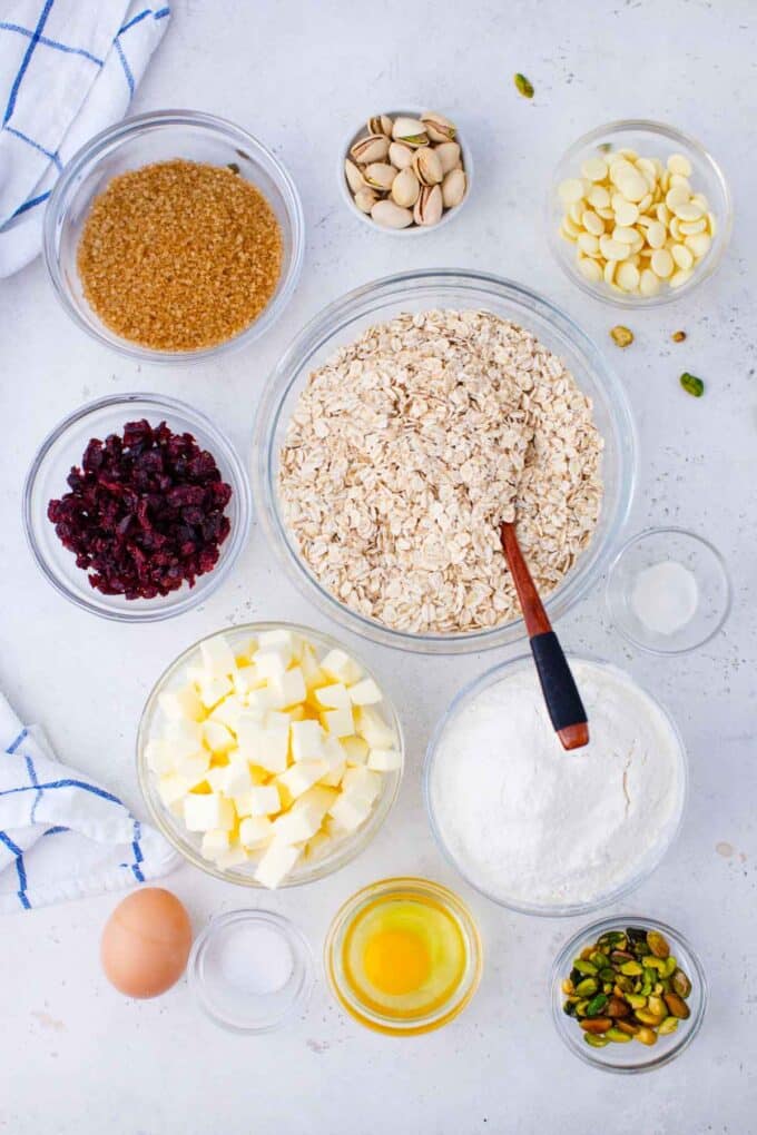 cranberry pistachio oatmeal cookies ingredients arranged in bowls on a white surface