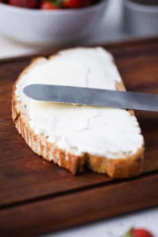 spreading cream cheese on a slice of bread