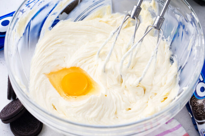 Beating cream cheese and eggs in a bowl.