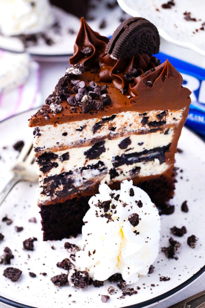 A slice of dream extreme Oreo cake served with a dollop of whipped cream.