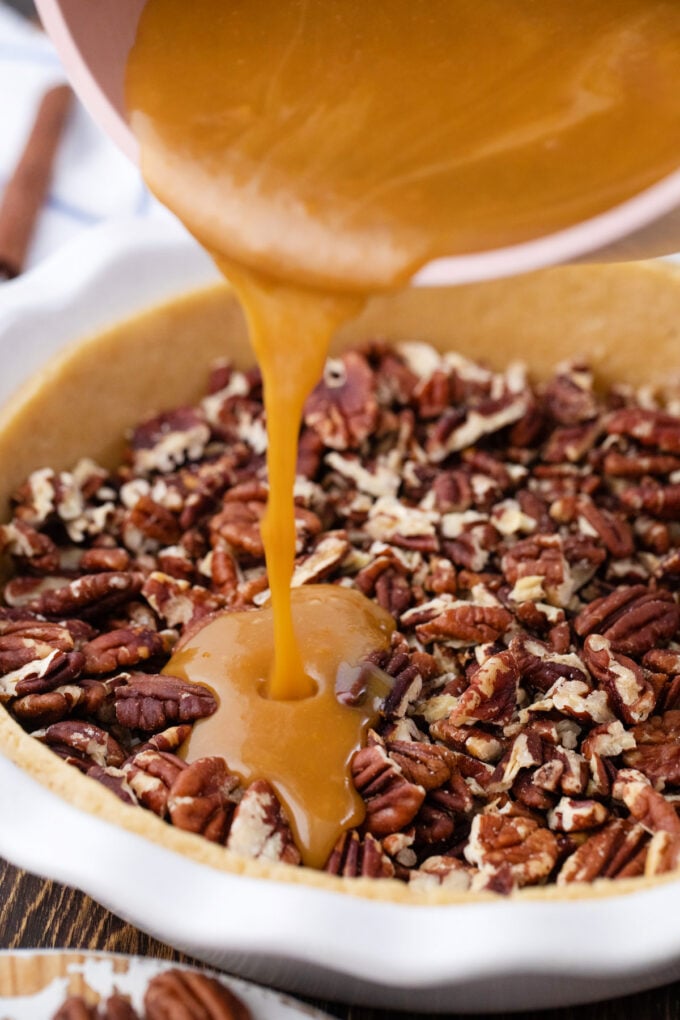Pouring pecan pie filling over chopped pecans.