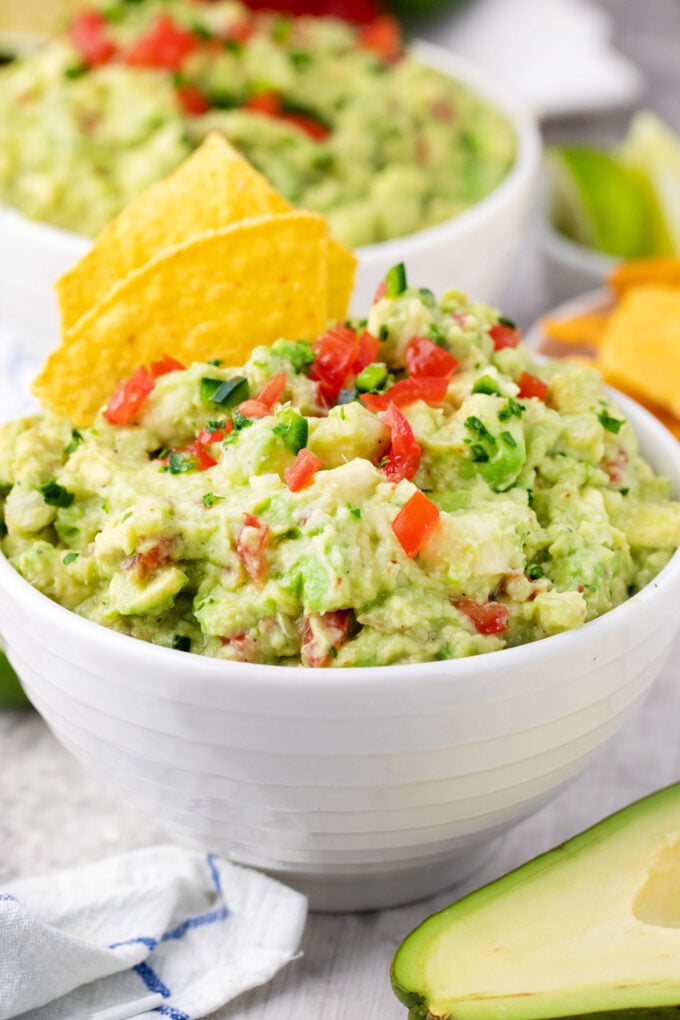A bowl of Mexican guacamole with corn chips.