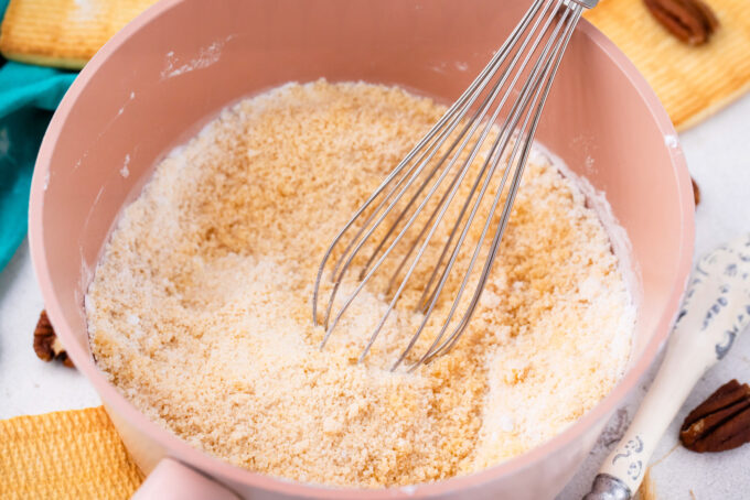 Whisking sugar and flour in a saucepan.