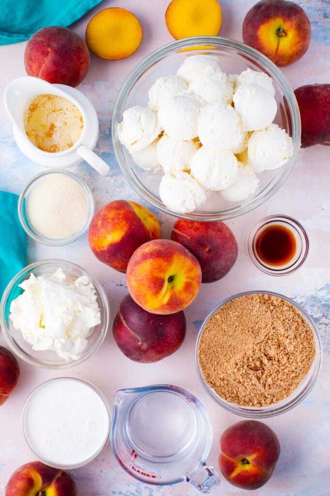 Overhead shot of no bake peach cheesecake ingredients in bowls on a light surface.