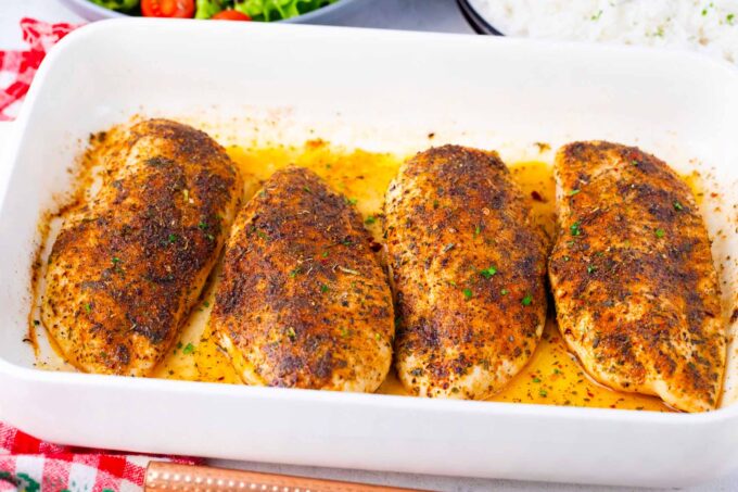Golden brown, oven baked chicken breasts in a baking dish.