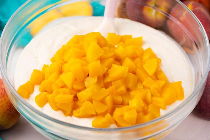 Stirring fresh chopped peaches into cheesecake batter.