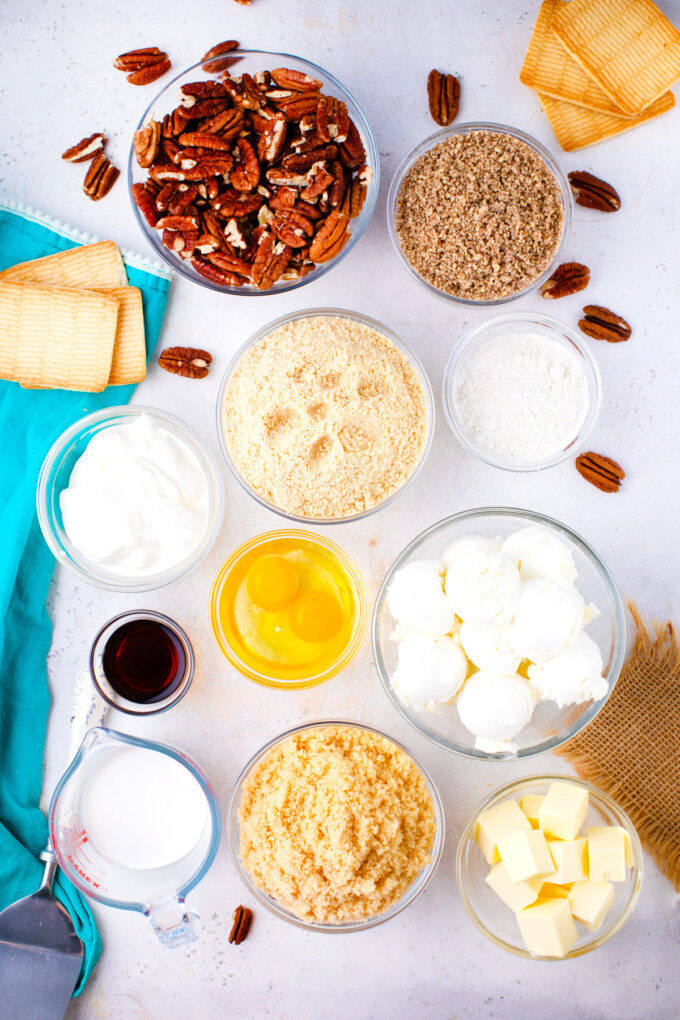 Overhead shot of pecan pie cheesecake ingredients in bowls on a table.