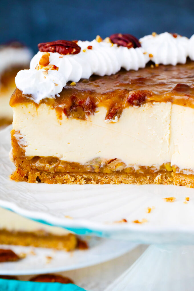 Sliced pecan pie cheesecake on a cake stand.
