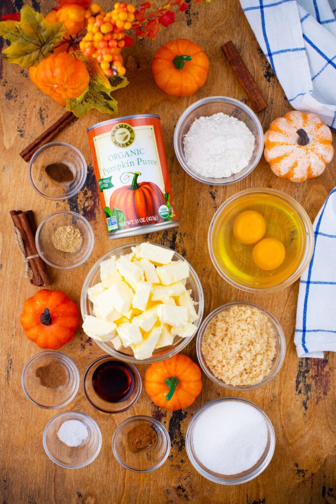 Overhead shot of pumpkin pie ingredients in bowls on a wooden table.