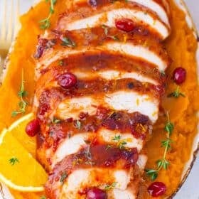 overhead shot of sliced roasted cranberry orange turkey breast on a serving plate with mashed sweet potatoes