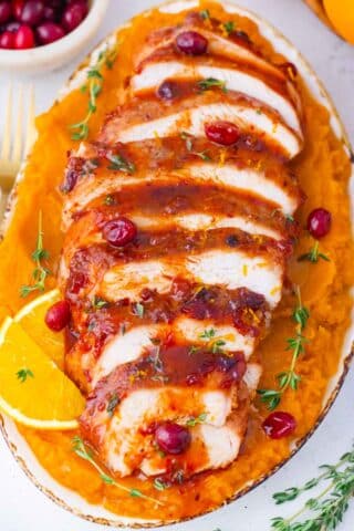 overhead shot of sliced roasted cranberry orange turkey breast on a serving plate with mashed sweet potatoes