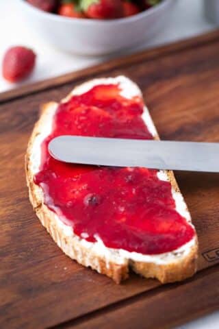 sourdough bread slice topped with cream cheese, strawberry jam