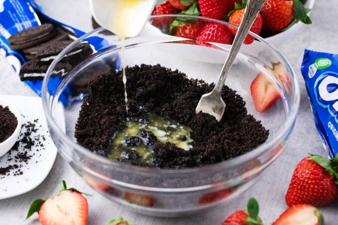 Mixing crushed Oreos and butter.