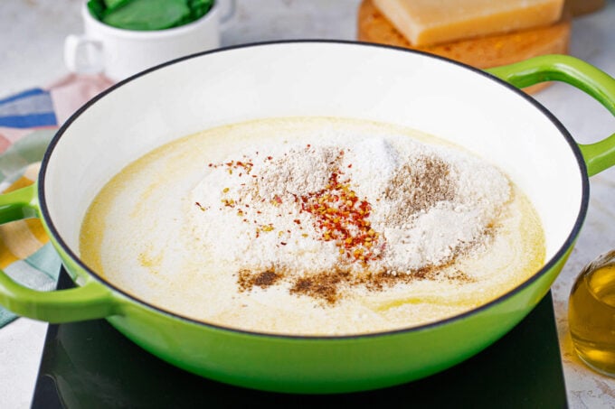 Adding grated Parmesan cheese to creamy sauce.