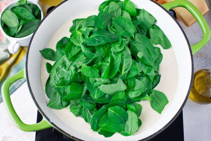 Adding spinach to creamy Parmesan sauce.