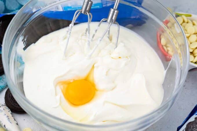 Whisking eggs into cheesecake batter.