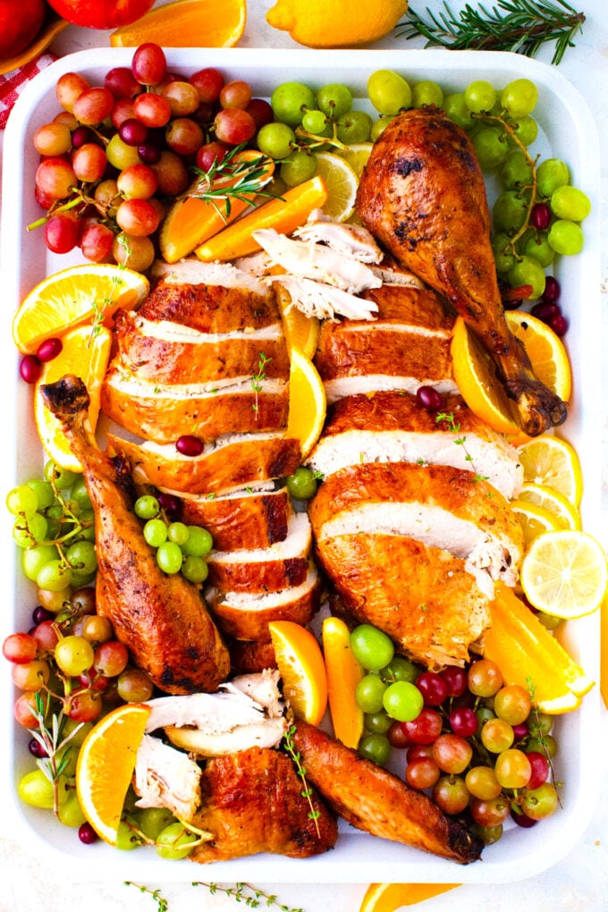 Carved oven roasted turkey on a platter with lemon and grapes.