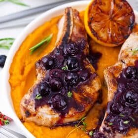 overhead shot of blueberry pork chops topped with blueberry saace and served with a grilled lemon half