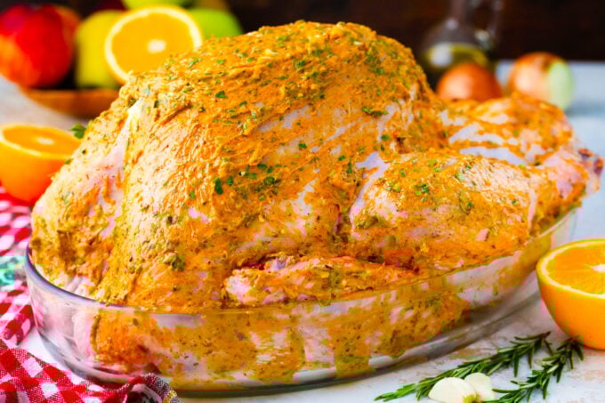 Whole turkey coated in orange herb butter mixture.