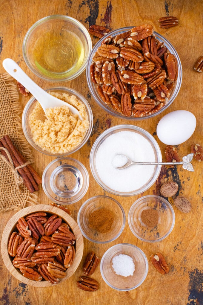 Overhead shot of candied pecans ingredients in bowls on a wooden surface.