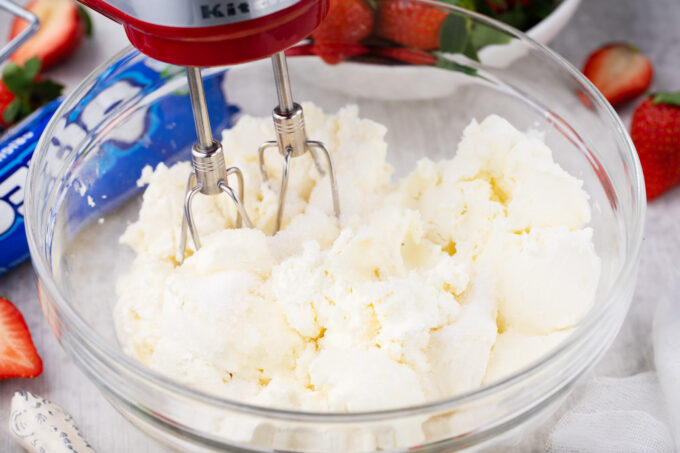 Beating cream cheese.