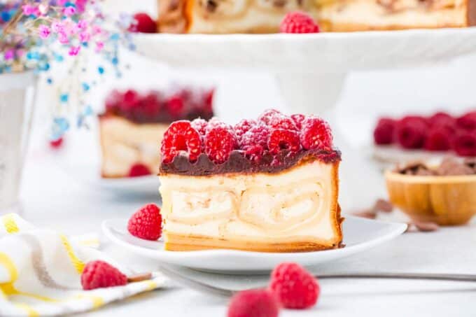 slices of crepe stuffed new york cheesecake with chocolate ganache and raspberries