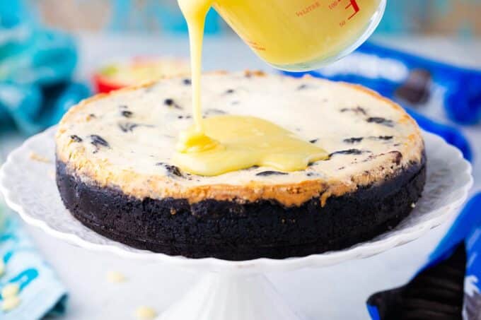 Pouring white chocolate ganache on Instant Pot Oreo cheesecake.