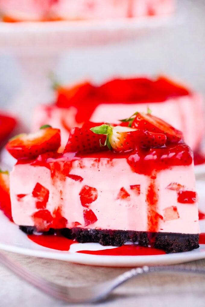 A slice of no-bake strawberry cheesecake with an Oreo crust.