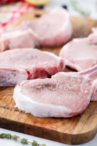 bone-in pork chops seasoned with salt and pepper on a cutting board