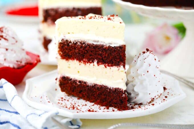 red velvet cheesecake cake on a plate with whipped cream on the side